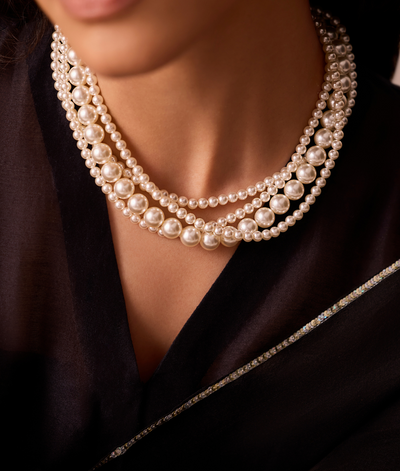 Pearl necklace worn by a person against a dark background